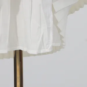Detalle del dobladillo plisado blanco que muestra costuras y textura de calidad