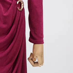 Close-up of magenta long-sleeved dress with gold buckle and elegant draped detail.