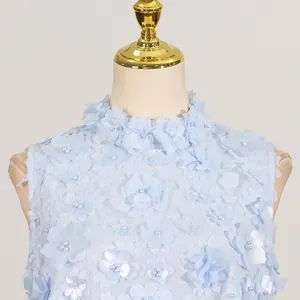 Close-up of light blue summer dress featuring 3D floral appliqués and delicate pearl beads