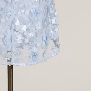 Close-up detail of light blue dress featuring 3D floral appliqués and pearl beads.
