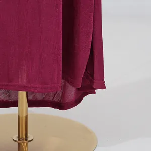 Macro detail of a burgundy autumn dress hemline showing fine stitching and textured fabric.