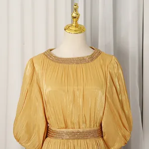 Close-up of elegant French vintage gold long dress with pleated fabric and beaded collar