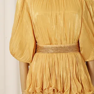 Detailed macro view of the gold pleated fabric and beaded belt on a French dress