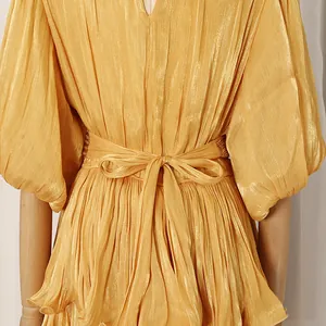Close-up of elegant pleated golden dress showing waist bow tie and fabric texture