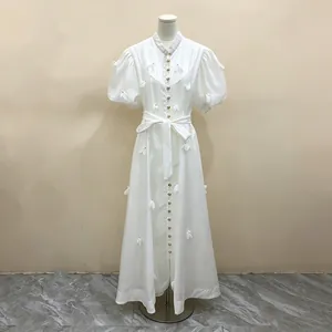 Détail d'une élégante robe longue blanche de style français avec fleurs 3D et boutons dorés