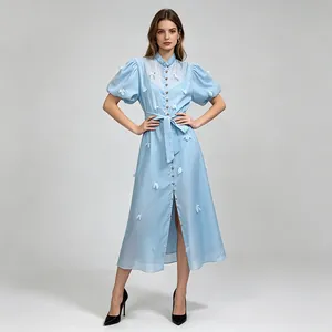 Détail d'une robe midi française bleu clair avec manches bouffantes et fleurs 3D