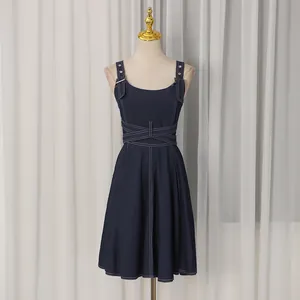 Frontansicht des dunkelblauen Denim-Trägerkleids mit Taillenkreuz und weißen Nähten