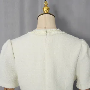 Detailansicht des Rückenausschnitts und Reißverschlusses eines weißen Tweed-Minikleides