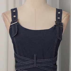 Detailaufnahme eines dunkelblauen Denim-Latzkleides mit verstellbaren Schnallenträgern.