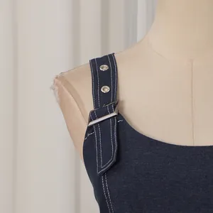 Nahaufnahme des dunkelblauen Denim-Kleidträgers mit Metallschnalle und weißen Nähten