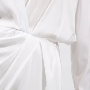 Close-up of elegant V-neckline and pleated high-waist detail on a white minimalist midi dress