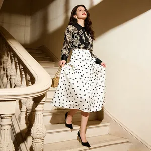 Model wearing an elegant high-waist polka dot A-line midi skirt on a grand staircase