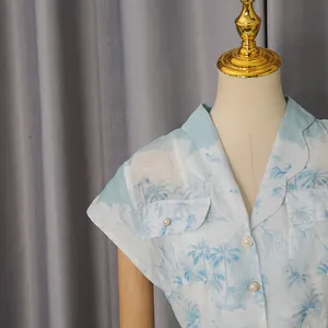 Détail de la robe chemise à imprimé palmier avec col à revers et boutons perles.