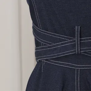 Detailaufnahme eines dunkelblauen Jeanskleids mit asymmetrischem Gürtel und Kontrastnähten