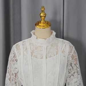 Detailed view of an elegant white floral lace dress with ruffled collar and long sleeves.
