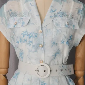 Détail robe chemise imprimé tropical avec boutons perle et ceinture blanche