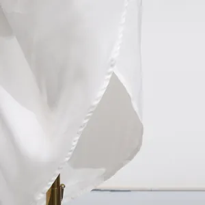 Detailed close-up of white dress hemline featuring elegant asymmetric overlapping slit design
