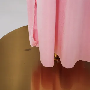 Dettaglio dell'orlo di un abito asimmetrico rosa che mostra la trama del tessuto lucido