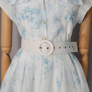 Détail de la robe chemise à imprimé palmier avec ceinture blanche et boutons
