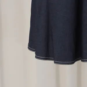 Detailansicht der weißen Kontrastnähte am Saum eines dunkelblauen Jeanskleides