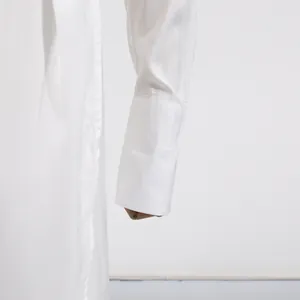 Close-up detail of a white dress sleeve featuring a wide minimalist cuff design.