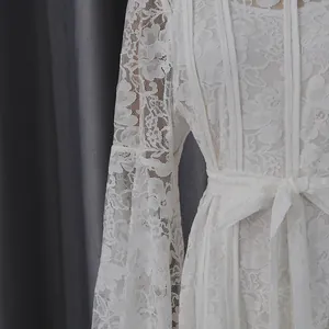 Detailed view of elegant white floral lace long-sleeve dress featuring a waist tie design