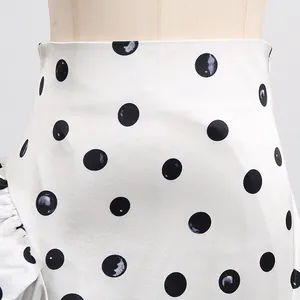 Detailed view of white high-waist A-line skirt with black polka dots and side zipper closure