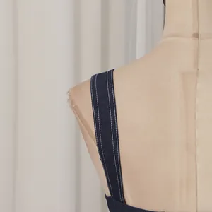 Detailansicht eines Trägers aus dunkelblauem Denim mit weißen Doppel-Kontrastnähten
