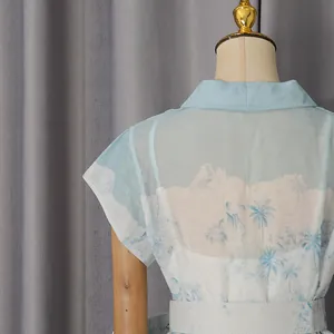 Vue détaillée du dos d'une robe chemise bleu clair à imprimé palmier tropical et voile
