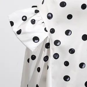 Close-up view of a white A-line midi skirt featuring black polka dots and elegant ruffle details