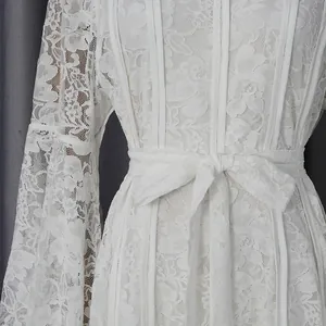 Close-up detail of a white floral lace dress with waist tie and flared sleeves