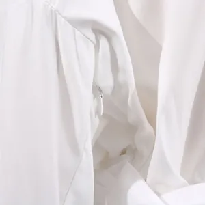 Close-up view of the high-quality invisible zipper on a white V-neck high-waist dress.