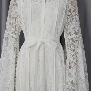 Close-up of white elegant lace dress with a tied waist and bell sleeves