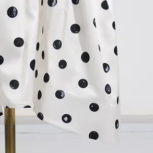 Close-up of white midi skirt with black polka dots showing fabric texture and hem
