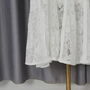 Close-up detail of exquisite white floral lace fabric on elegant spring dress hemline.