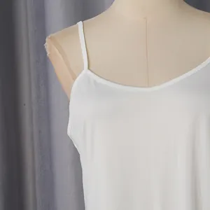 Gros plan sur l'encolure et les fines bretelles d'un caraco blanc sur un mannequin de couture.
