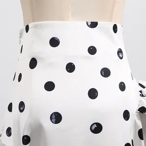 Detail view of high-waisted white skirt with black polka dots and hidden zipper.