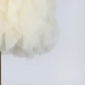 Detail view of lightweight cream fabric with elegant layered ruffles on a summer dress