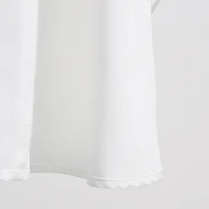 Close-up detail of white A-line skirt hemline showing delicate stitching texture