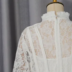 Close-up of white lace dress back detail showing ruffled stand collar and zipper