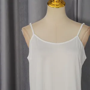 Close-up of white camisole neckline on a mannequin with gray curtain background.