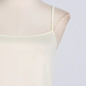 Detail shot of elegant cream camisole strap and smooth neckline on a mannequin