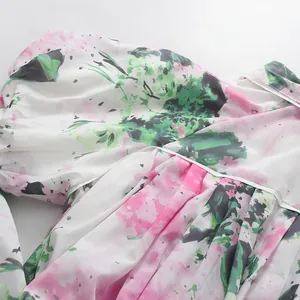 Detailaufnahme des lebhaften Blumenmusters auf einem weißen Chiffonkleid mit Puffärmeln