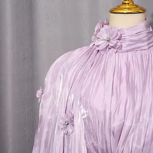 Detail view of purple pleated maxi dress with 3D floral neckline appliqués