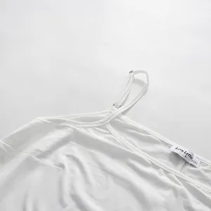 Detailansicht der verstellbaren Schultergurte und des Etiketts am weißen Kleid