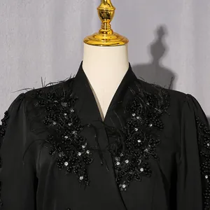 Detailansicht des eleganten schwarzen Kleides mit handgefertigten Strass und Federn.
