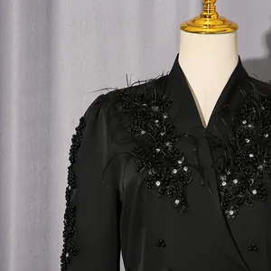 Detailansicht eines schwarzen Blazers mit eleganten Feder- und Strassapplikationen.