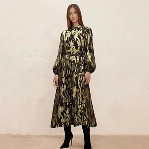 Elegant long-sleeved dress featuring a metallic gold pattern and black stiletto boots