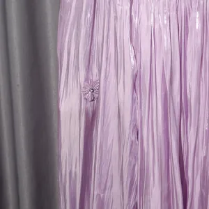 Close-up of pleated lavender dress featuring a decorative floral applique with rhinestone