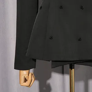 Nahaufnahme von eleganten schwarzen Blazer-Details mit schwarzen Perlenakzenten.
